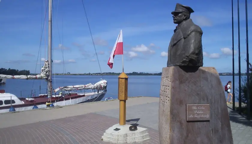 Pomnik upamiętniający zaślubiny Polski z morzem. Obok żaglowiec i polska flaga.