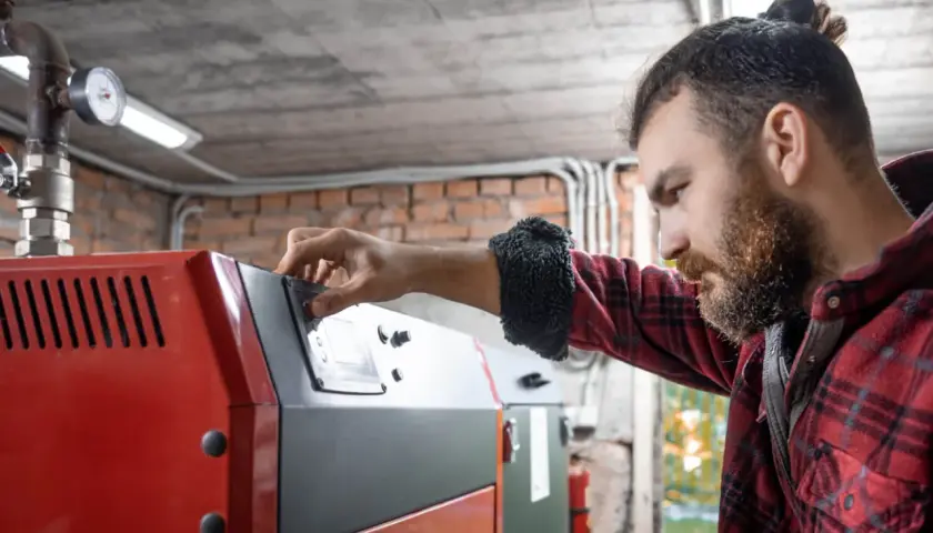Mężczyzna reguluje panel sterowania pieca na ekogroszek.