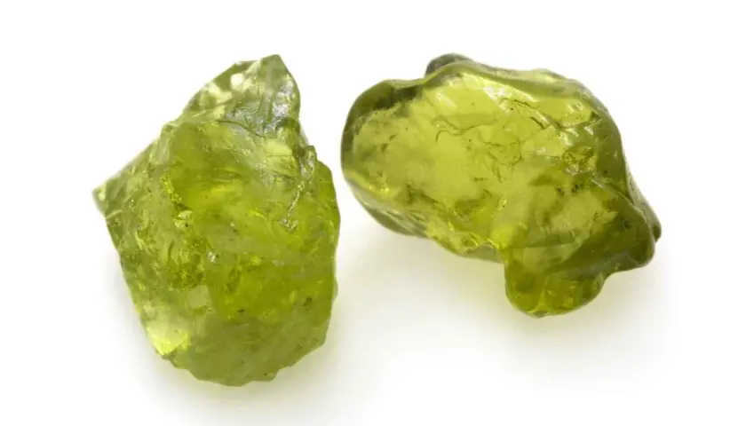 Zwei rohe Peridot-Kristalle in leuchtendem Grün. Ihre natürliche **Peridot Wirkung** soll angeblich das Herz öffnen und positive Energie fördern.
