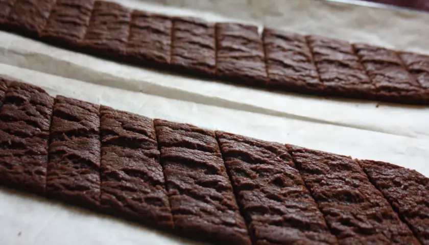 Två långa rader med nybakade chokladsnittar på bakplåtspapper. Perfekt för ett chokladsnittar recept.