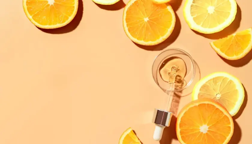 Krople serum z witaminą C w pipetce, otoczone plasterkami pomarańczy i cytryny. Pamiętaj, z czym nie łączyć witaminy C.
