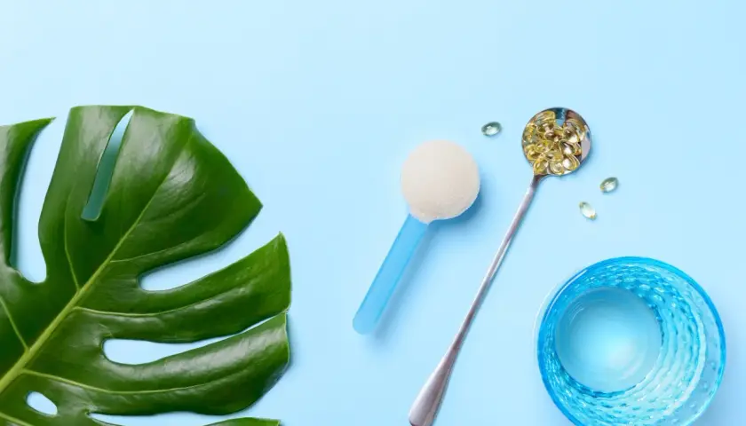 Grünes Monstera-Blatt, Löffel mit Kapseln, Pulver und Glas Wasser. Alles für die gleiche Wirkung.