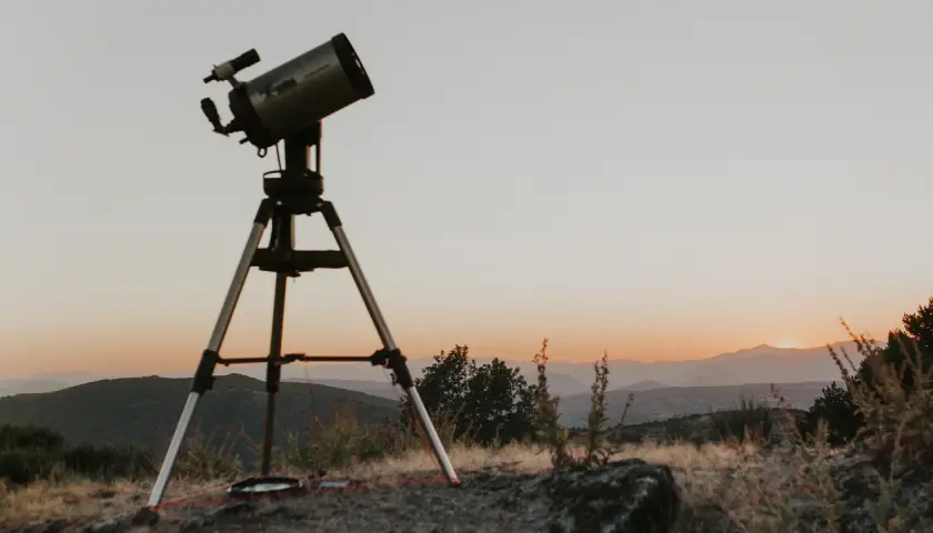 Telescopi preparat per a un sopar amb estrelles. El cel s'enfosqueix sobre les muntanyes, prometent una nit d'observació celestial.