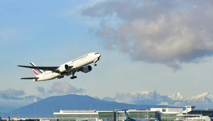 Samolot Air France wznosi się nad lotniskiem, a w tle widać ośnieżone góry. Idealny widok dla tych, którzy zastanawiają się, jak szukać lotów czarterowych.
