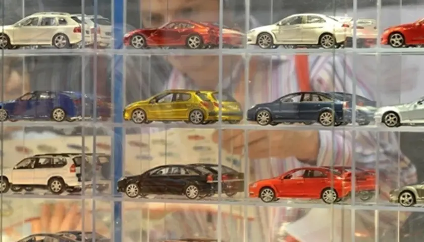 Modele samochodów w gablotach: białe kombi, czerwony sportowy, żółty hatchback, niebieski sedan, srebrny coupe.