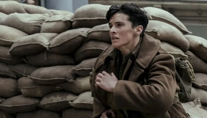 En ung soldat, en del av rollistan i Dunkirk, gömmer sig bakom sandsäckar.