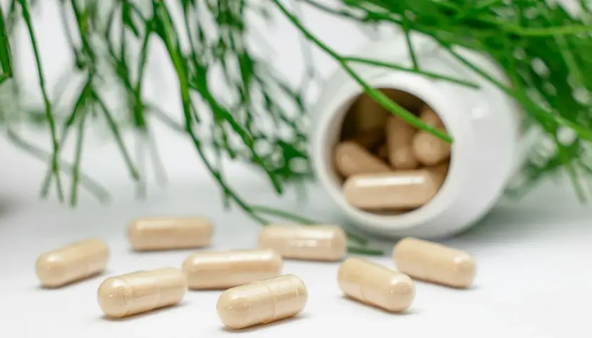 Kapseln und grünes Blattwerk. Mögliche Wechselwirkung Magnesium Blutdrucksenker? Natürliche Heilmittel im Fokus.