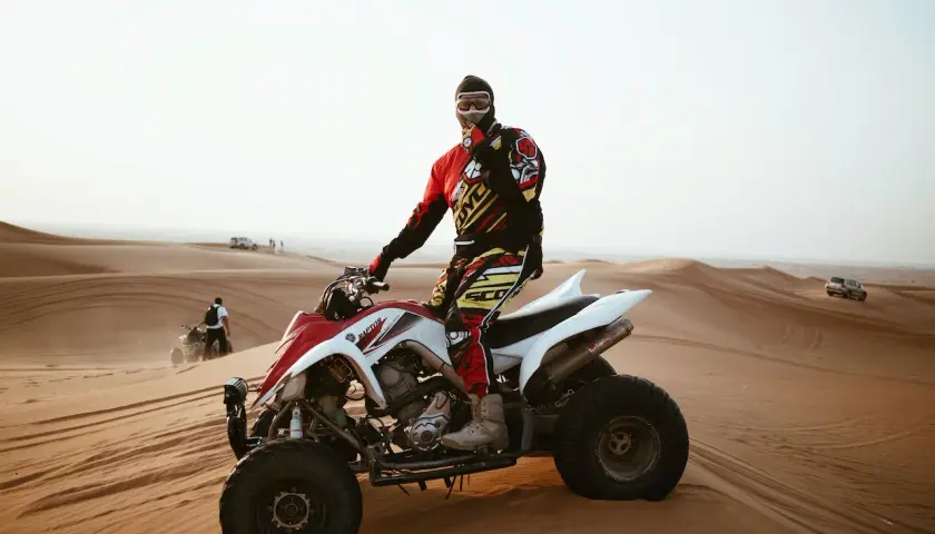 Mężczyzna w stroju motocyklowym siedzi na quadzie na pustyni.