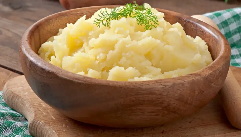 Puszyste puree ziemniaczane w drewnianej misce, ozdobione koperkiem. Idealne jako alternatywa dla masła, gdy zastanawiasz się, co dodać do ziemniaków.