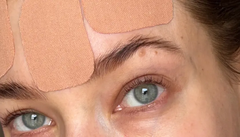 Närbild på ögon och panna med tejpremsor för face taping.