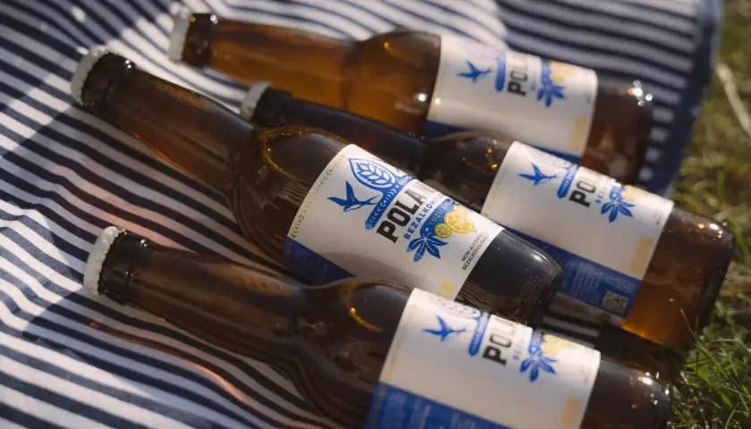 Butelki piwa bezalkoholowego POLAN leżą na kocu. Czy piwo zero ma alkohol? Nie, to piwo jest bezalkoholowe.