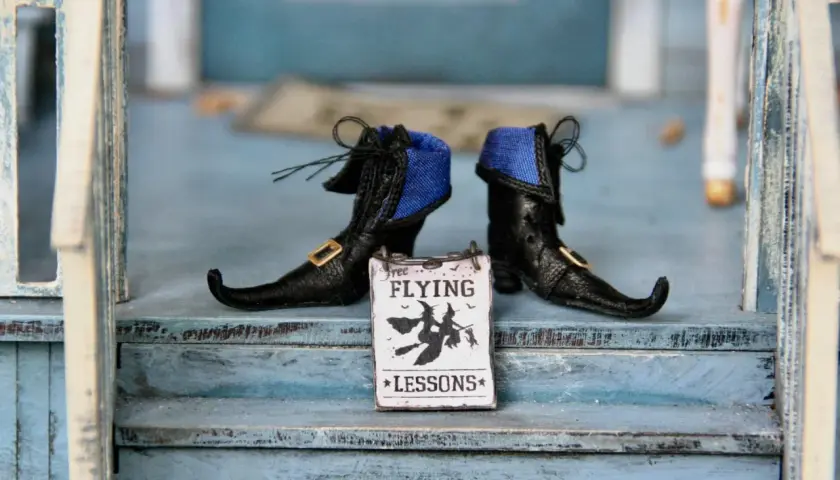 Stivaletti da strega neri con un cartello "Free Flying Lessons" per le parole di Halloween.