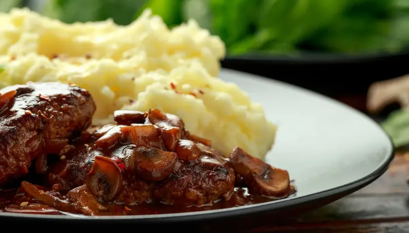 Délicieuses joues de bœuf mijotées dans une sauce aux champignons, servies avec une purée de pommes de terre onctueuse.
