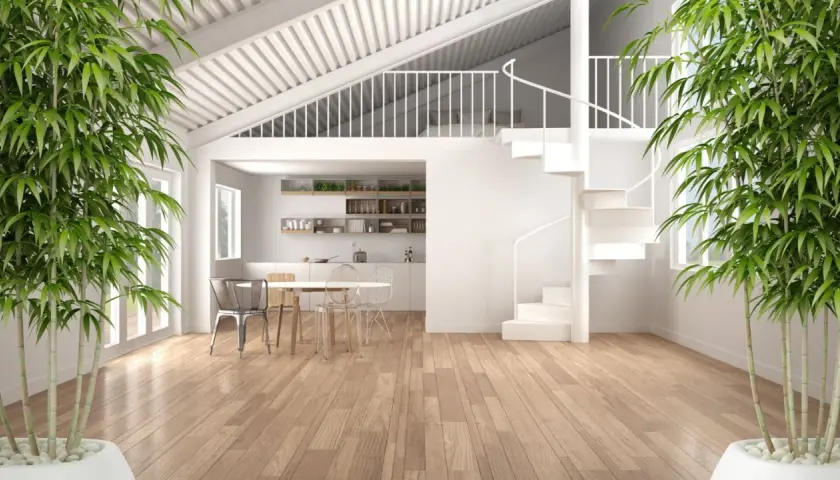 Interno moderno con cucina, tavolo e sedie. Una scala a chiocciola bianca porta a un soppalco a vista. Bambù verde incornicia la scena.