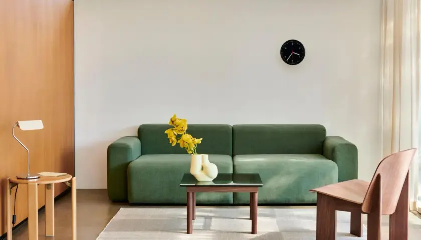 Grünes Sofa, Holzsessel und Beistelltisch im skandinavischen Einrichtungsstil. Ein moderner Wohnbereich mit minimalistischer Ästhetik.