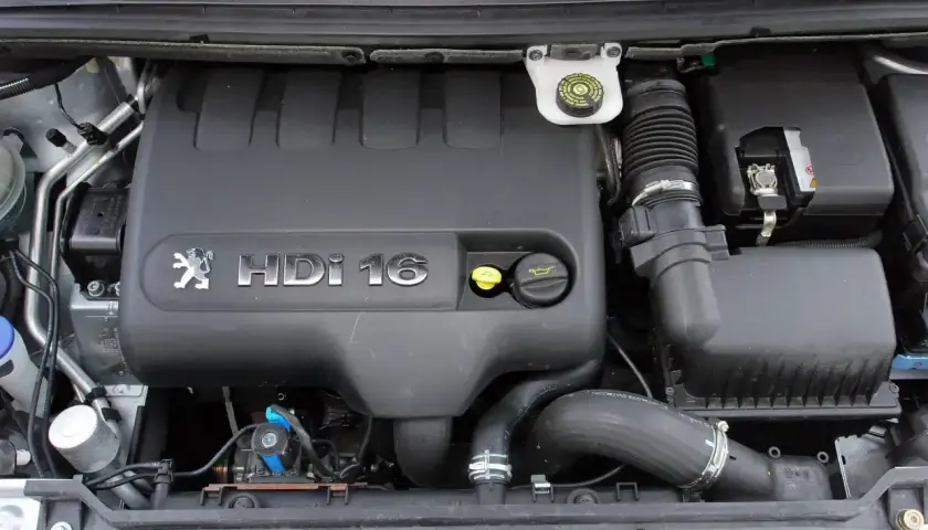 Silnik Peugeot 307 2.0 HDi 16V. Widoczny czarny plastikowy kolektor, zbiorniczek płynu hamulcowego i elementy układu dolotowego.