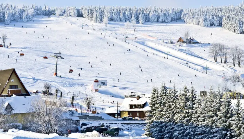 Stok narciarski w Karkonoszach, idealne miejsce na ferie zimowe 2026 dolnośląskie. Narciarze szusują, kolejki wywożą na szczyt.