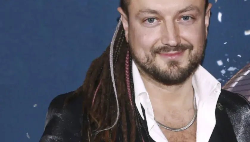 Aleksander Milwiw-Baron, znany z charakterystycznych dredów, z uśmiechem na twarzy. Jego pochodzenie jest często tematem dyskusji.