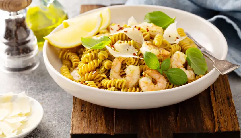 Pyszny makaron z ciecierzycy z krewetkami, cytryną i parmezanem, udekorowany bazylią.