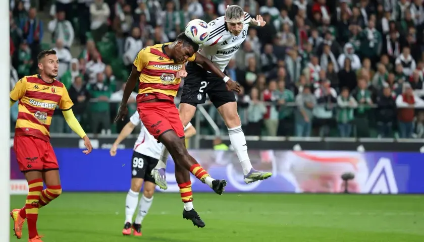 Piłkarze walczą o piłkę w powietrzu. W tle kibice, a na boisku emocje jak przy największych ekstraklasa transfery.
