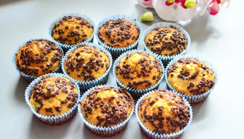 Urocze muffinki bananowe z czekoladą, posypane obficie czekoladowymi drobinkami, wyglądają apetycznie.