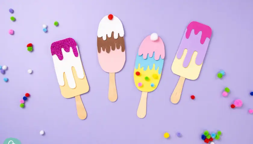 Bunte Eis-Kreationen zum Eis basteln, verziert mit Glitzer und Pompons, liegen auf lila Untergrund.