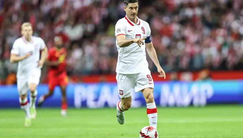 Robert Lewandowski, polska fałszywa dziewiątka, prowadzi piłkę na boisku w białej koszulce z numerem 9.