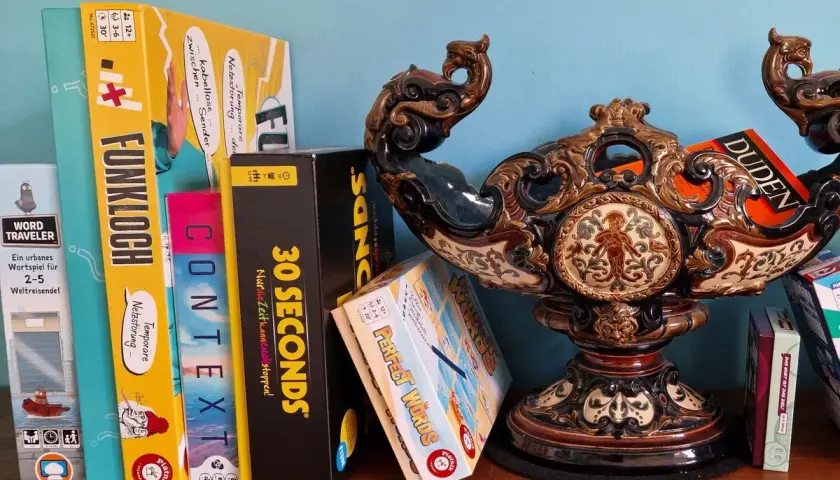 Brettspiele wie "Funkloch" und "30 Seconds" warten darauf, dass ihr Wort erraten wird. Ein Duden-Buch liegt daneben.