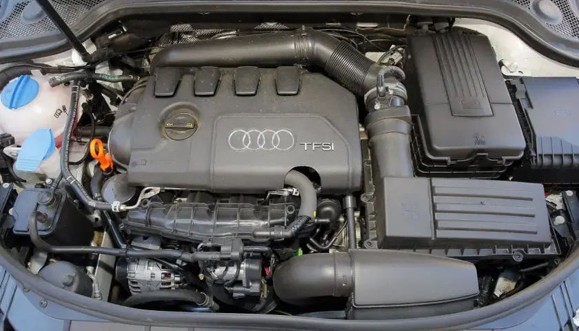 Silnik TFSI w Audi 8P, widok z góry. Widać pokrywę silnika z logo Audi, elementy układu dolotowego i filtry.