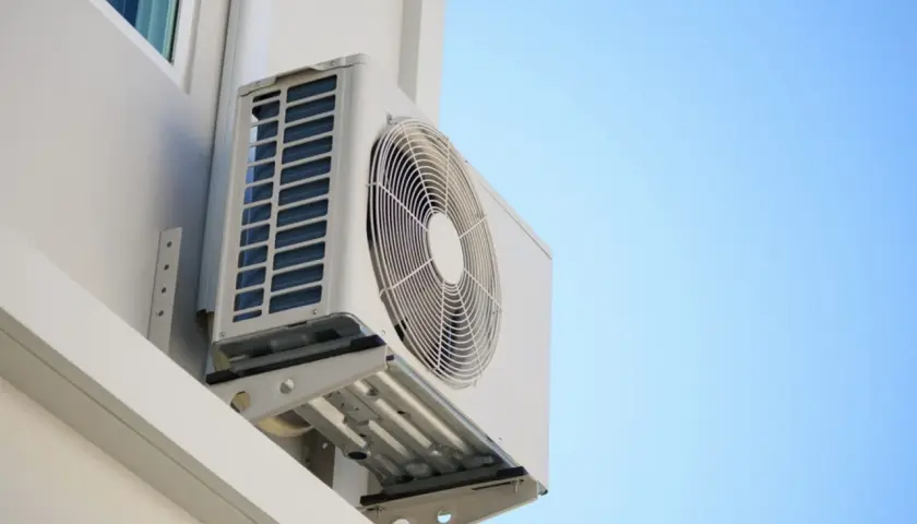Unidad exterior de aire acondicionado montada en pared blanca, ideal para saber donde colocar la unidad exterior del aire acondicionado para una óptima ventilación.