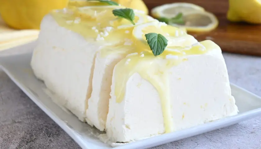 Un delizioso semifreddo al limone, guarnito con scorzette, menta e una glassa gialla. Perfetto per un dessert rinfrescante.