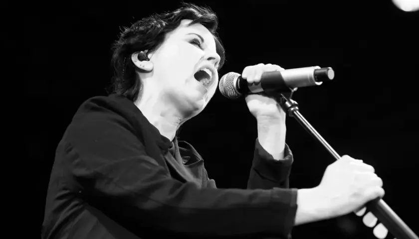Dolores O'Riordan, jedna z członkiń The Cranberries, śpiewa do mikrofonu z pasją.