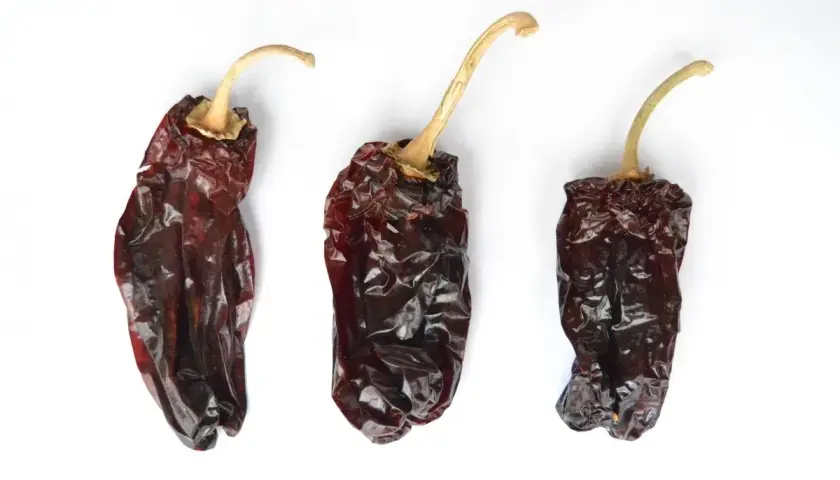 Tres pimientos choriceros secos, oscuros y arrugados, listos para dar sabor a guisos y salsas.