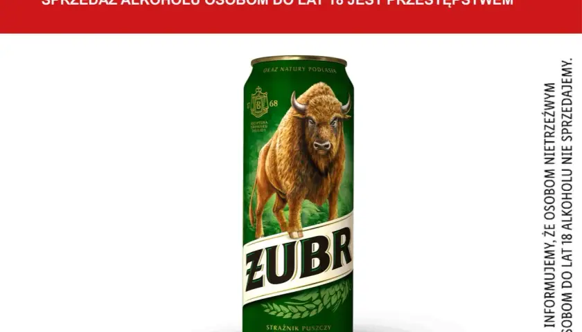 Puszczańskie piwo Żubr, z wizerunkiem żubra i napisem "Strażnik Puszczy". Informacja o zawartości alkoholu w piwie.