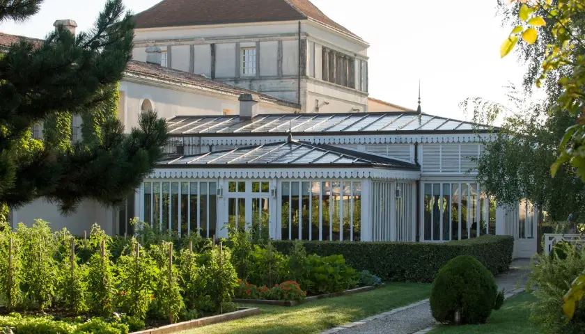 Jardin luxuriant devant une serre élégante, rappelant la beauté du caudalie vignoble.
