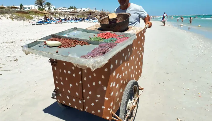 Sprzedawca na plaży w Tunezji oferuje słodycze. Może to być okazja do wymiany drobnych na pyszności, bo tunezja waluta to dinar.
