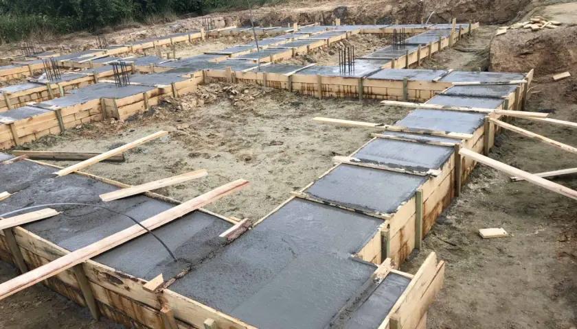 Szalunki na fundamenty z wylanym betonem. Widać zbrojenie. To pierwszy krok, jak obliczyć beton na fundament.