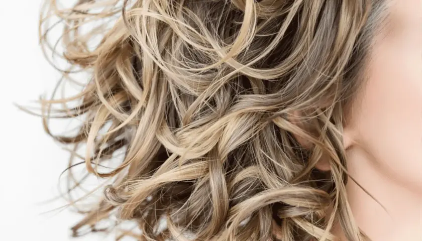 Cabello rubio ondulado y sedoso, libre de sulfatos y parabenos, con reflejos dorados.