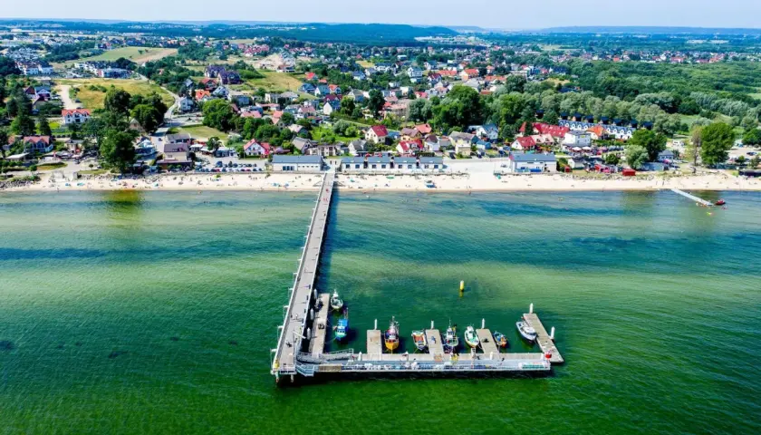 Mechelinki - warto jechać! Widok na molo, plażę i urokliwą nadmorską miejscowość.