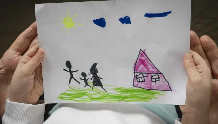 Disegni psicologia test bambini: una famiglia stilizzata cammina verso una casa rosa sotto un sole giallo e nuvole blu.