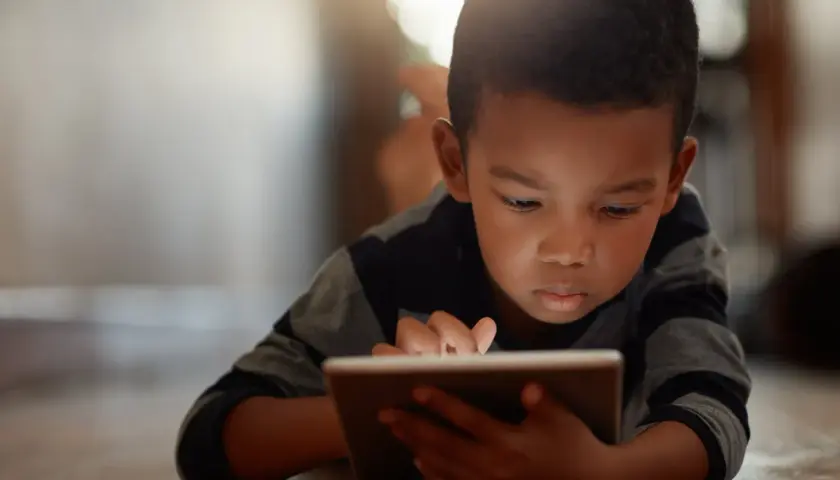 Un niño concentrado en su tablet, un ejemplo de cómo los niños introvertidos exploran mundos digitales.