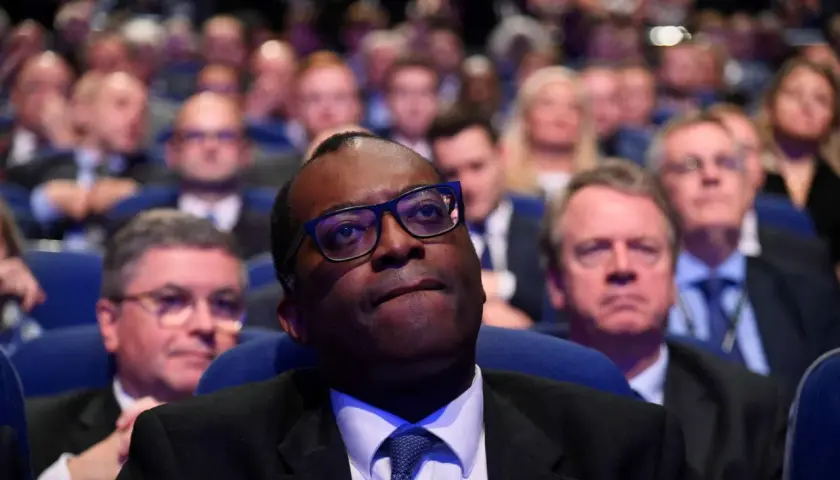 A man in glasses looks up, surrounded by a blurred audience. This scene captures a moment of collective attention, hinting at the shared experience and what is social impact.
