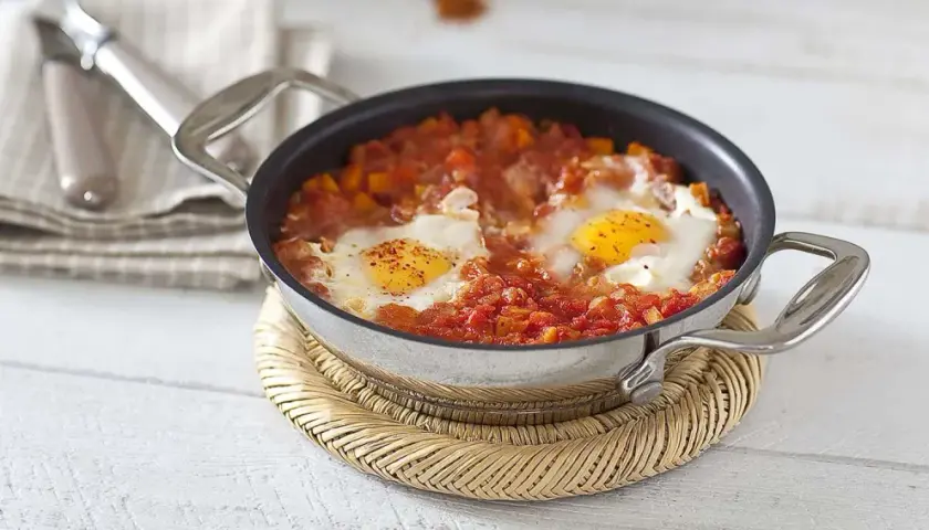 Un plat d'oeuf tomate mijoté dans une poêle, avec des poivrons et des épices. Un délice pour le petit-déjeuner.