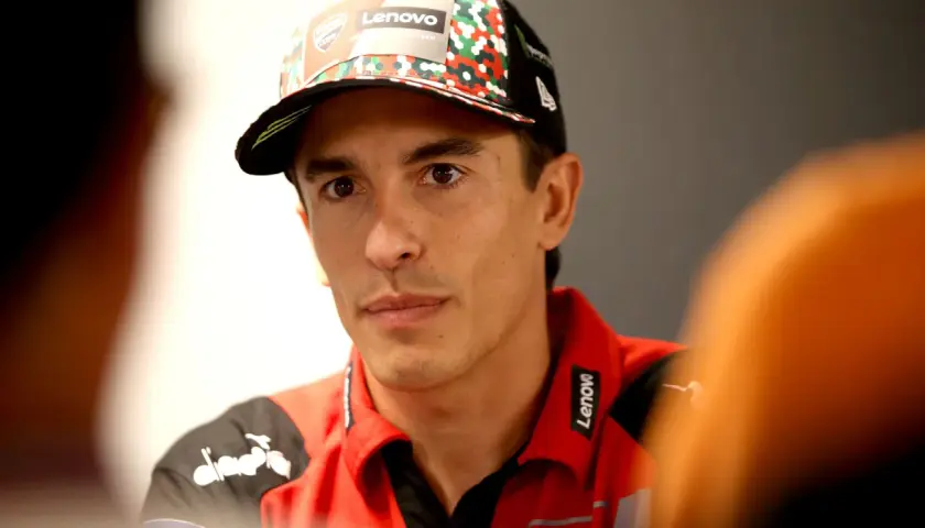 El piloto Marc Márquez, con su físico atlético, luce una gorra del equipo y una polo roja con el logo de Lenovo.