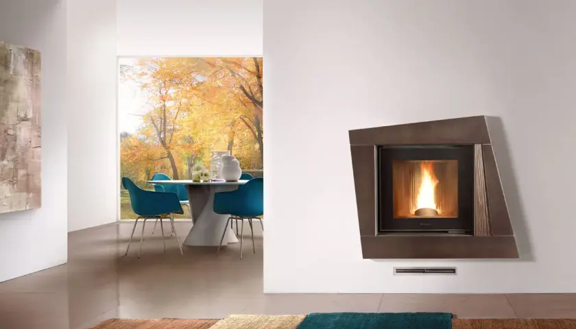 Stufa a pellet nel camino moderno, con fiamme vive, in un soggiorno con vista su un giardino autunnale.