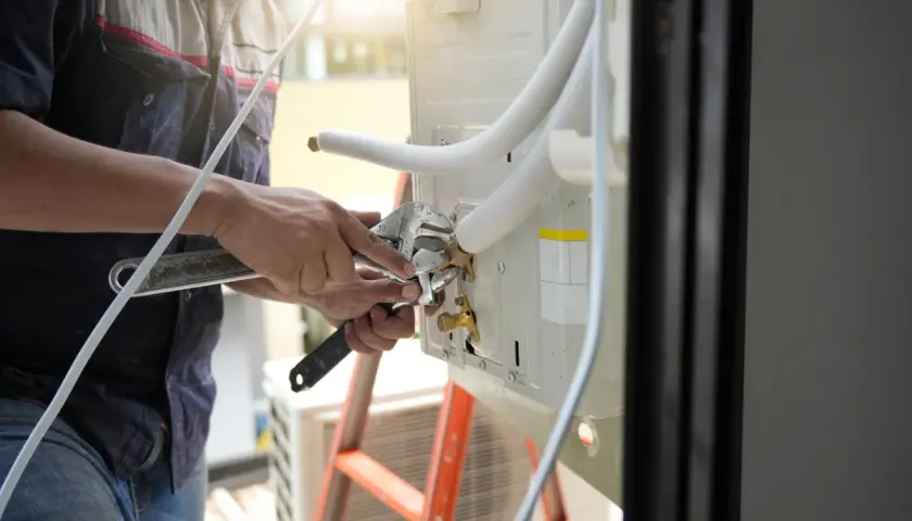 Técnico ajustando conexión para como cambiar el tubo de desague del aire acondicionado.