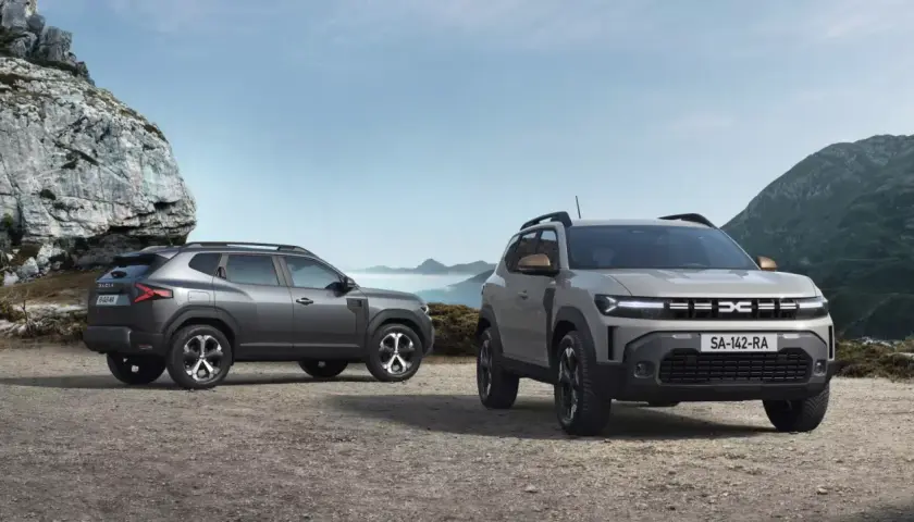 Dwa nowe SUV-y Dacia Duster, idealne na wyprawy do 40 tys. zł, stoją na kamienistym podłożu w górskim krajobrazie.