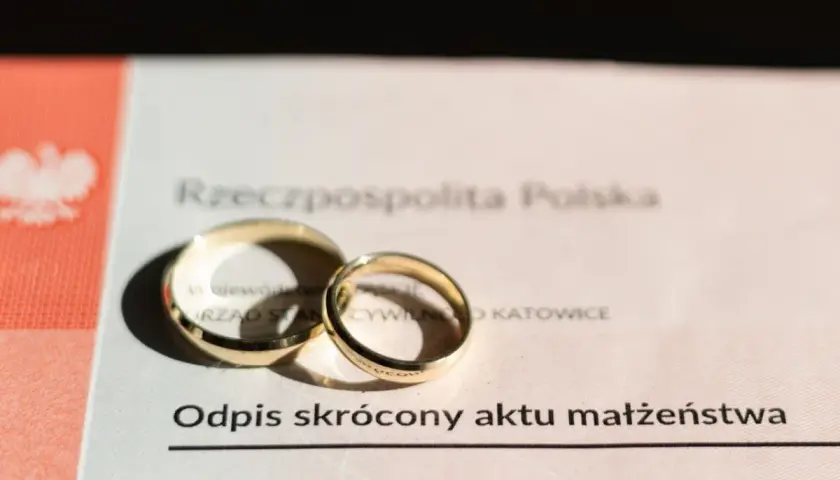 Złote obrączki na odpisie skróconym aktu małżeństwa. Zastanawiasz się, ile kosztuje akt małżeństwa? Dokument z pieczęcią Urzędu Stanu Cywilnego w Katowicach.