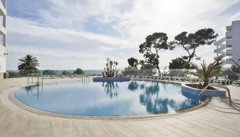 Basen przy hotelu Best Negresco, z leżakami i palmami, w tle morze i błękitne niebo.