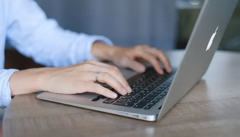 Mani su tastiera di un laptop, con anello nuziale. Lavoro da remoto per ottenere myecm crediti.